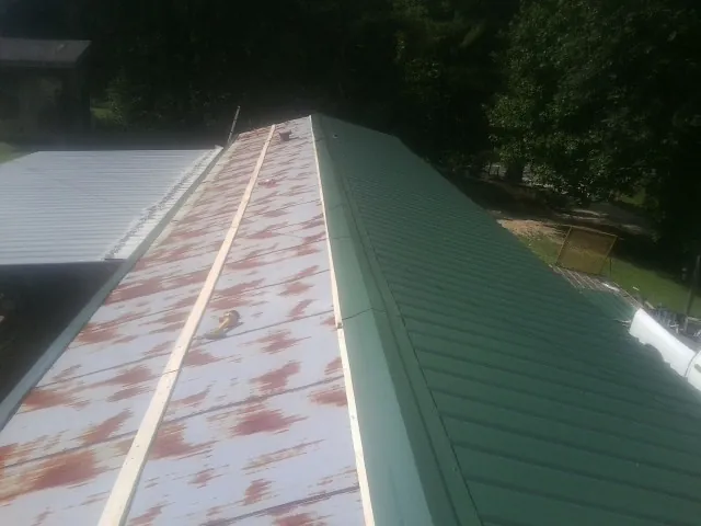 Old rusted panels beside newly installed green metal roofing — Wind Damage Roof Repair by Roofing Brothers in Midvale