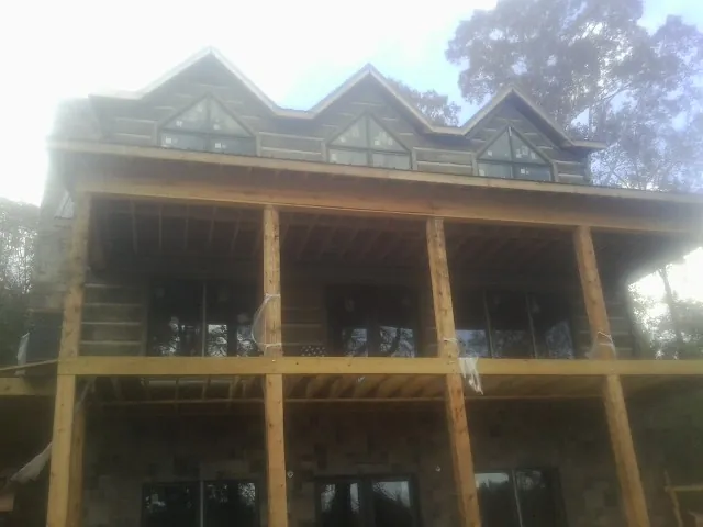 Dormers and porch framing on a large log home under construction — Roof Coating work by our crew in Midvale