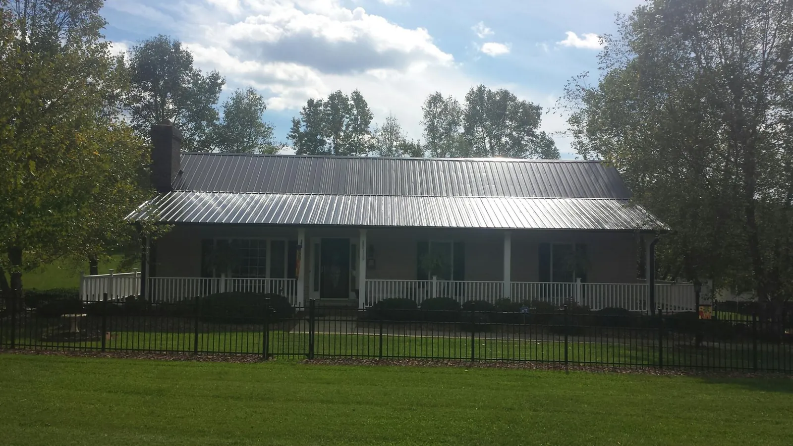Gray metal roof on a brick ranch with a full width front porch — Gutter Guard Installation work by our crew in Midvale