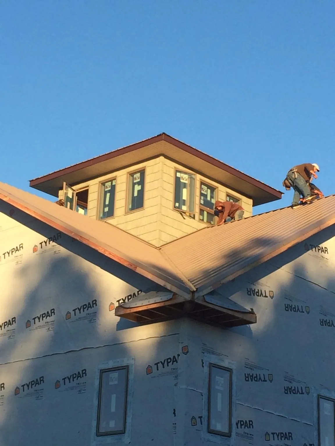 Roofers working around a rooftop cupola on a new metal roof at sunset — Roof Waterproofing in Midvale by Roofing Brothers